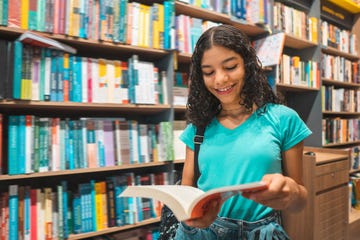 teenager girl reading book in library