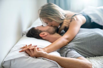 couple kissing on bed holding hands