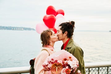 couple holding heartshaped balloons kissing while exploring city