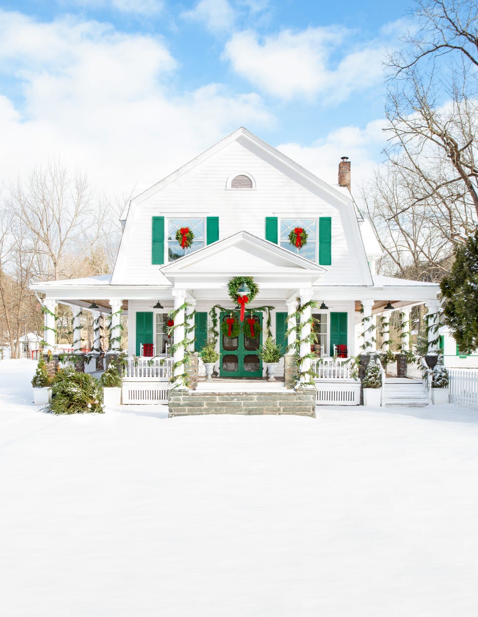 white and green exterior houes with snow decorated for christmas