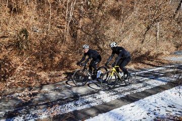 two cyclists riding on a snowy road