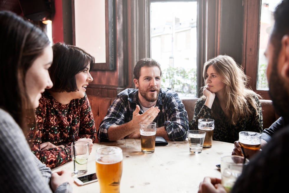 group of friends at a pub having a discussion while drinkings beeers