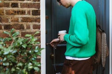 a young man leaving home in the morning, locking the door with his keys