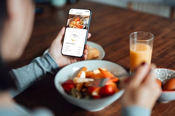 young woman using mobile app to track nutrition and count calories with smartphone