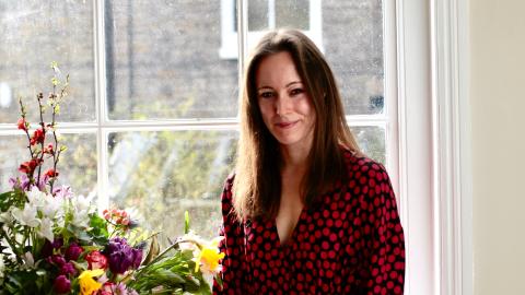 Dr Amy Boyington standing by a window next to some flowers