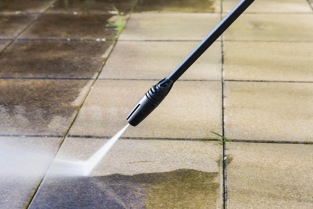 a pressure washer spraying a patio