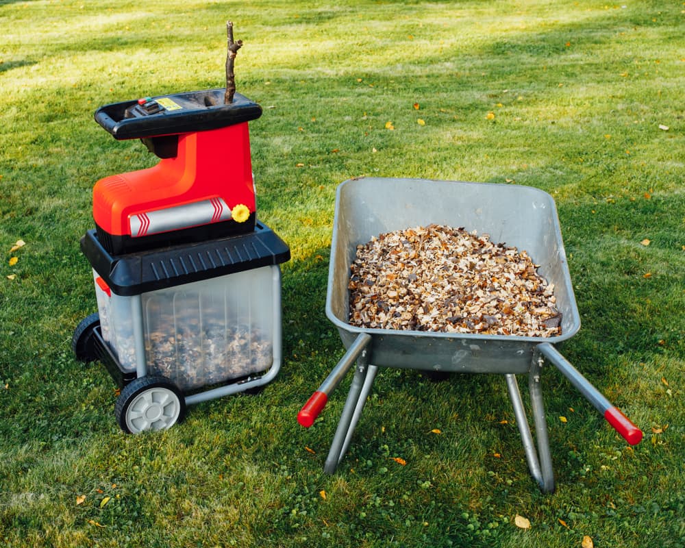 a garden chipper with wood chippings in a steel wheelbarrow