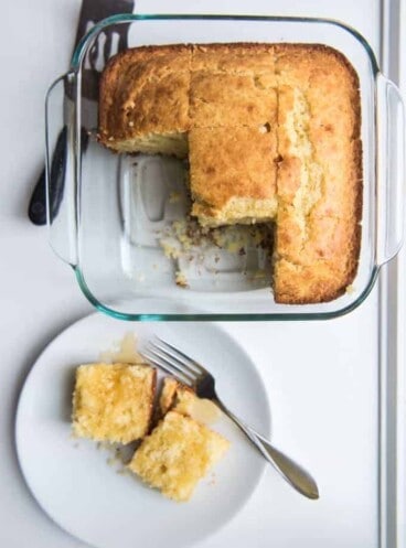 Homemade cornbread in a square baking dish with some slices removed.