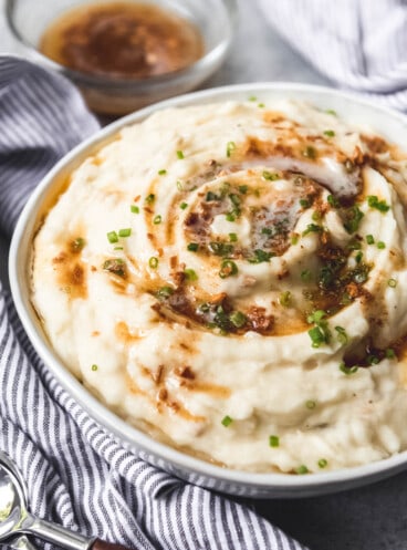 Garlic brown butter mashed potatoes in a bowl with garnish.