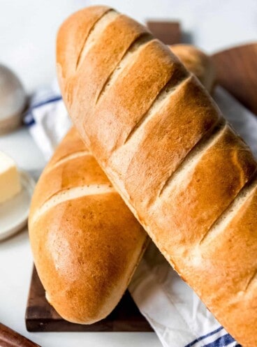 A loaf of homemade French bread stacked on top of another loaf.