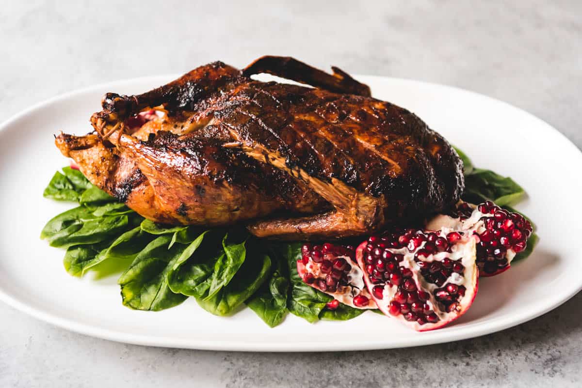 An image of a whole roasted duck on a serving platter for an alternative Thanksgiving dinner.