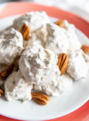 Old fashioned divinity and pecans on a red and white plate.