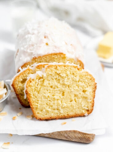 A slice of coconut bread in front of the rest of the loaf.