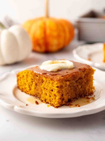 A slice of pumpkin cornbread on a plate with butter and honey on top.