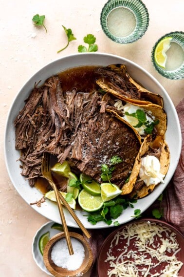 Bowl filled with shredded Mexican brisket and corn tortillas for making tacos.