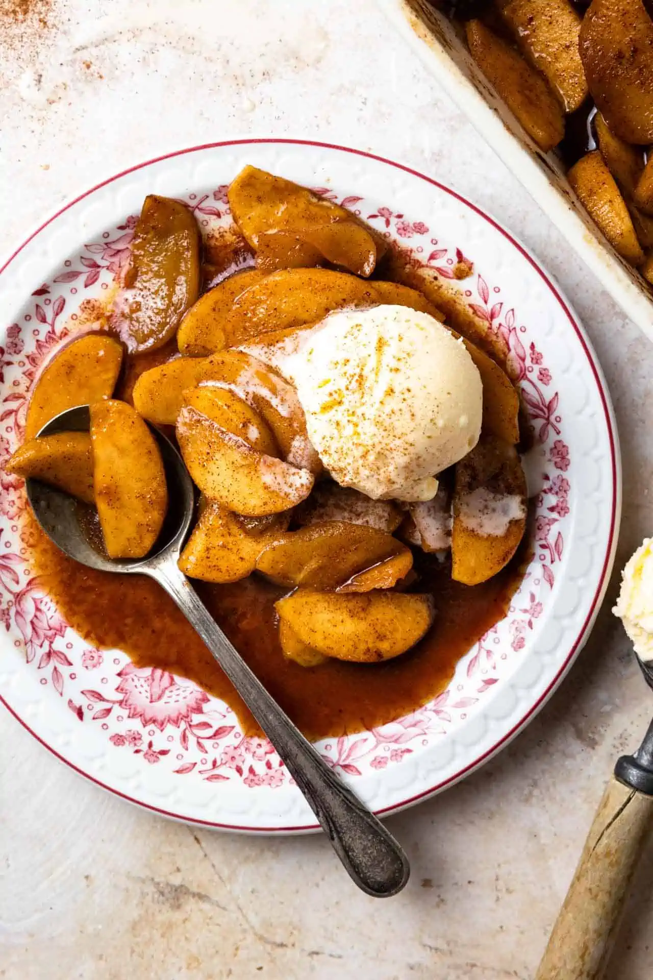 Bowl of baked apples served with a scoop of vanilla ice cream. 