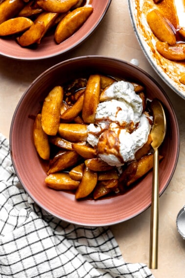 Overhead image of fried apples served in a bowl topped with a scoop of vanilla ice cream.