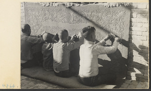 Carpet makers trimming a carpet with scissors