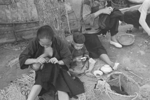 Mother breastfeeding while sewing, Shanghai