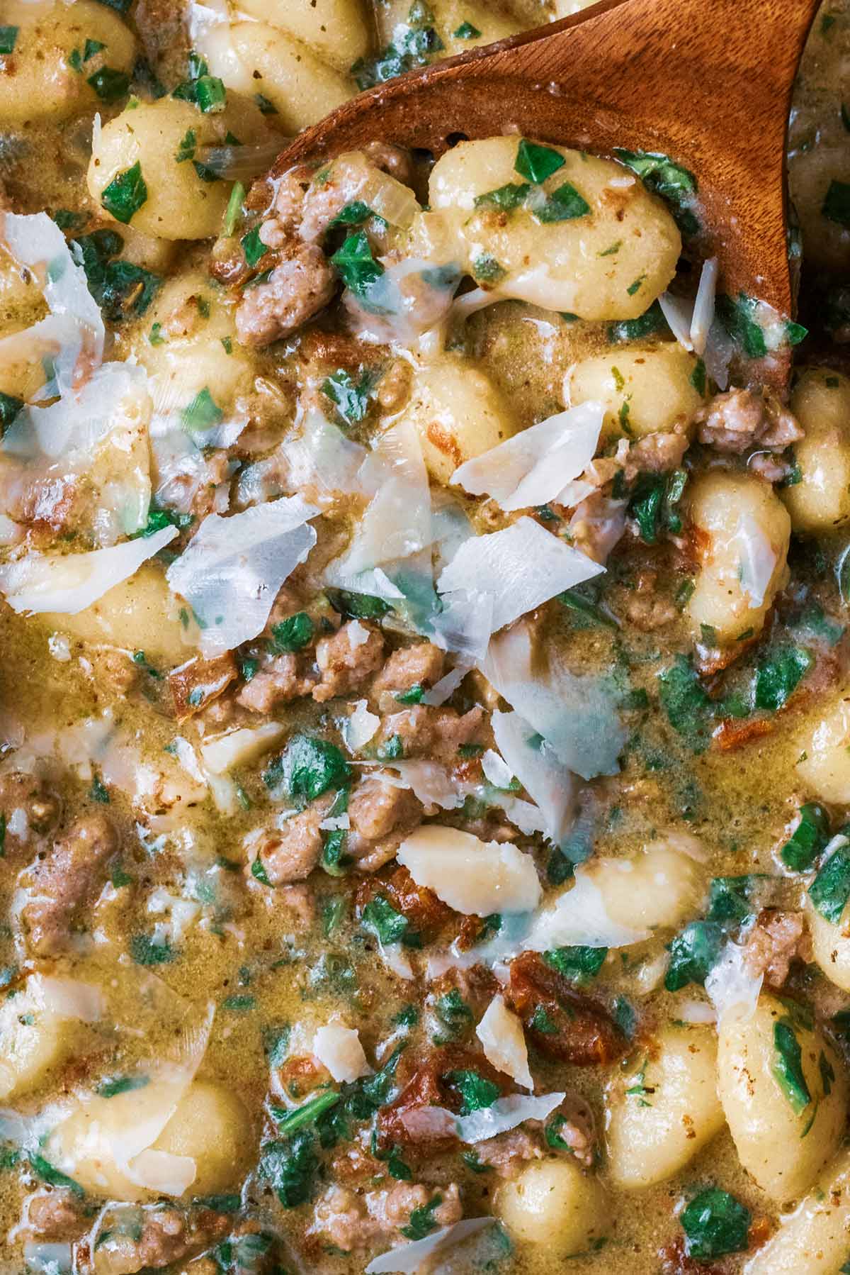 Parmesan shavings on top of cooked gnocchi in a creamy sauce.