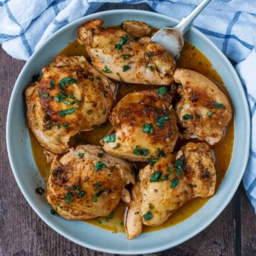 Six slow cooker chicken thighs in a round dish.