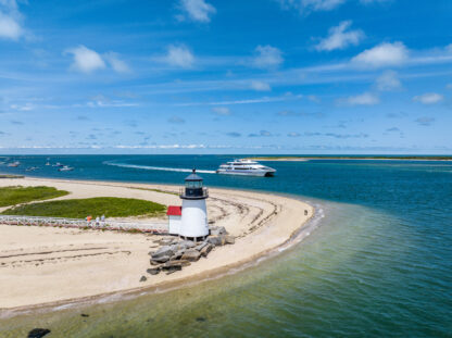 A lighthouse on a beach next to a boat.