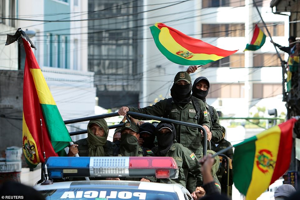 Police officers of the Tactical Police Operations Unit (UTOP) wave Bolivian flags while arriving to a police station during a protest against Bolivia's President Evo Morales in La Paz