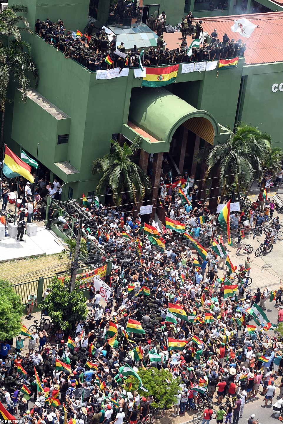 People gather outside the police headquarters as police officers stand on a terrace of the building, during protests against Bolivia's President Evo Morales, in Santa Cruz de la Sierra, Bolivia