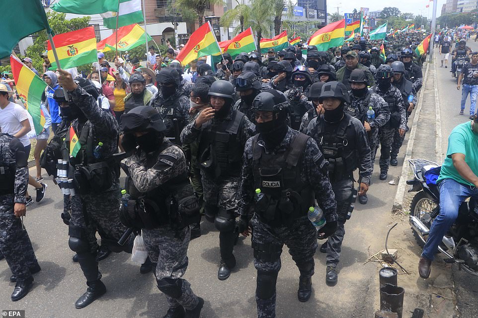 Policemen wave the tricolor flag of Bolivia while they retreat to a police station in the city of Santa Cruz, Bolivia