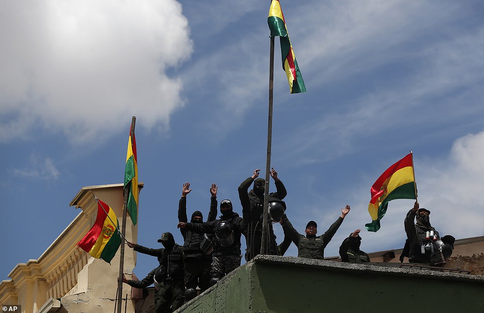 Presidential palace police guards who left their posts stand on the rooftop of a police station just meters away from the government building, in La Paz, Bolivia today