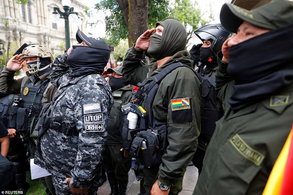 Police officers salute as the national flag is raised in front of the presidential palace, during a protest against Bolivia's President Evo Morales in La Paz, Bolivia