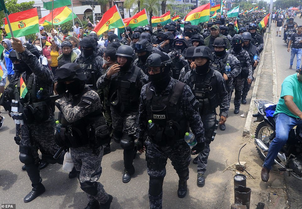 Policemen wave the tricolour flag of Bolivia while they tetreat to a police station in the city of Santa Cruz on November 9