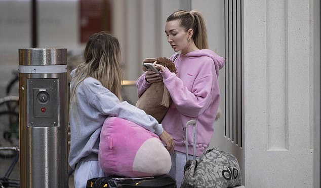 Kate stood patiently with a friend as they waited for the rented car to arrive to take away their bags