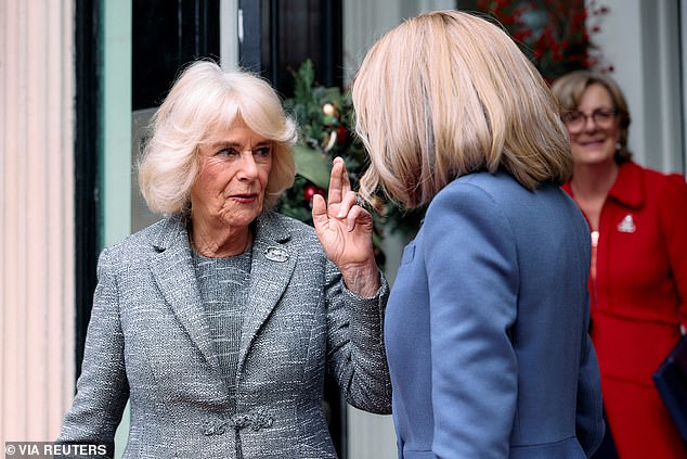 Queen Camilla crosses her fingers as she bids farewell to France's First Lady Brigitte Macron after the book prize ceremony in London today