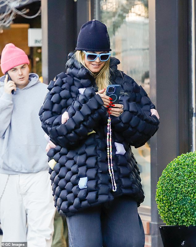 The blonde beauty added a black beanie and a pair of blue-rimmed sunglasses to her casual look