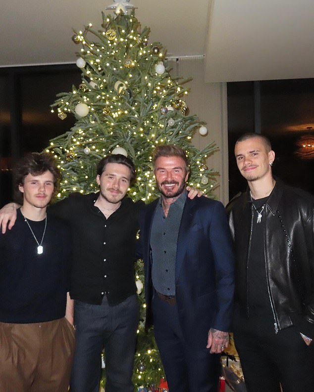 David Beckham pictured with his sons Cruz, Romeo and Brooklyn in front of the Christmas tree - the family celebrated Christmas abroad in Miami this year