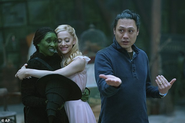 The plot of Wicked follows the friendship between Elphaba, a misunderstood young woman with green skin played by Cynthia Erivo, and Glinda, a popular rich girl played by Ariana Grande (Pictured: Cynthia Erivo wearing the braided wig, left, and Ariana Grande, with director Jon M. Chu)