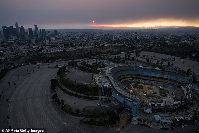 An aerial image shows the sun setting behind the downtown LA skyline and Dodger Stadium