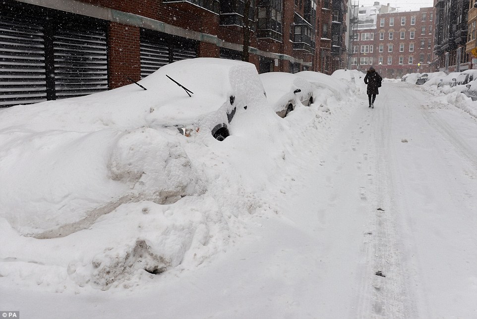 Hidden: A woman walks through snow-covered deserted streets in Boston on Monday as the snow shows no signs of stopping