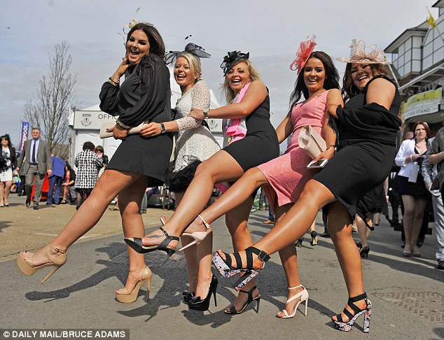 Raucous women in short dresses pose for pictures at Ladies' Day at the Grand National meeting in Aintree