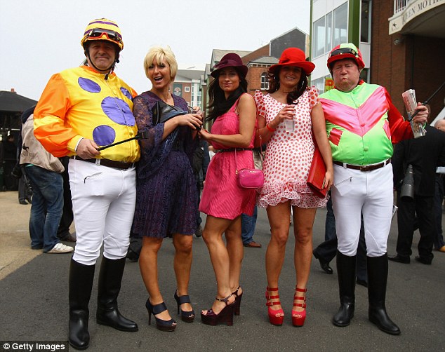 Two men dressed as jockeys pose for a photo with three ladies on ladies day during day two of the John Smith's Grand National meeting at Aintree