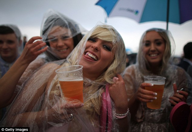 Women wear ponchos and drink beer in the rain during Ladies' Day at Aintree in 2012