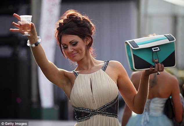 A woman holds a drink up at Ladies' Day at the Aintree Grand National meeting in April 2012