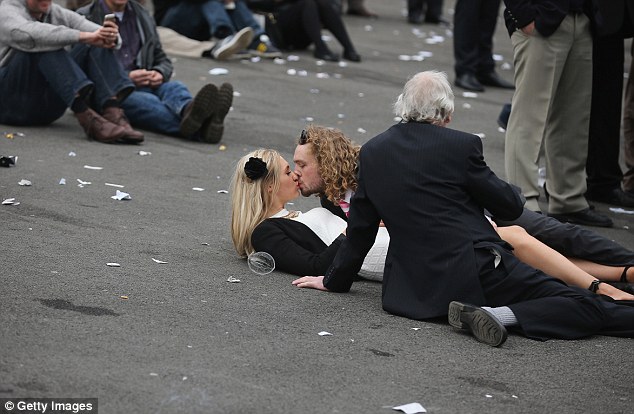 A couple kiss on the rubbish-littered ground at the Aintree Grand National Festival meeting last year