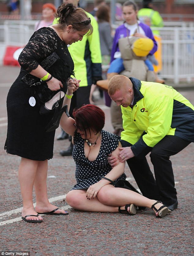 A woman is helped to her feet after tripping as she and racegoers make their way home from  Ladies' Day