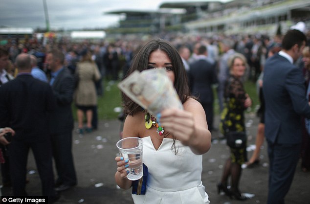 A woman shows off her winnings as racegoers enjoy the party atmosphere of Ladies' Day