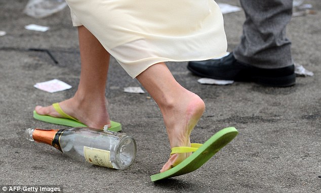 A reveller walks past an empty bottle of pink champagne wearing flip-flops 