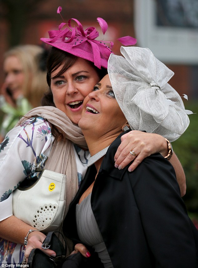 Female racegoers pull faces as the pose for pictures at Ladies' Day at the Grand National Festival meeting