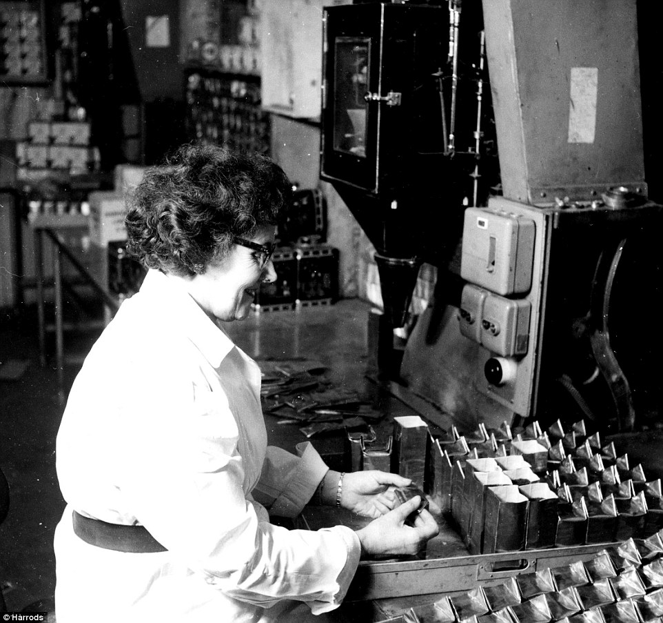 A members of staff in crisp white uniform folds closed hundreds of boxes of products for Harrods department store in the late 1920s