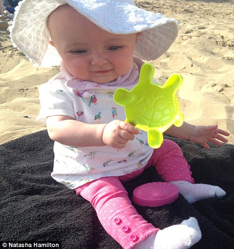 Baby Ella wearing a white sun hat and playing with a plastic tortoise toy, with her older brother, Harry